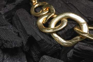 Golden necklace on black charcoal, closeup