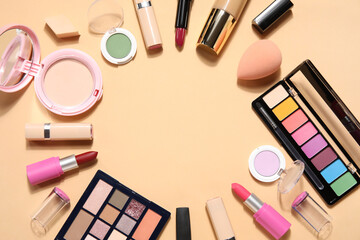 Frame made of decorative cosmetics with lipsticks on beige background