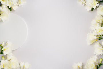 Fototapeta na wymiar Empty white round podium and freesia flowers on light grey background top view. Natural frame for cometic advertising. Pedestal for product presentation or sale mockup. Copy space. Minimal flat lay.
