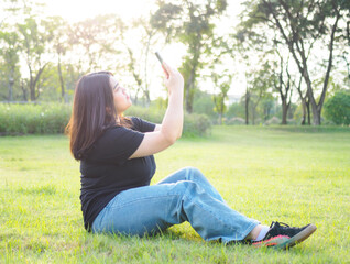 portrait young woman asian chubby cute beautiful one person wear black shirt look hand holding using smart phone in garden park outdoor evening sunlight fresh smiling cheerful happy relax summer day