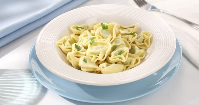 tortelloni on a plate. classic italian pasta with spinach and ricotta on a light background. dish of mediterranean cuisine. food on the table on a sunny day.