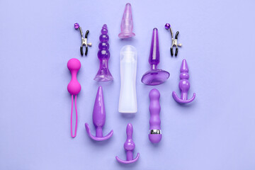 Bottle of lubricant and with vibrators and anal plugs on lilac background