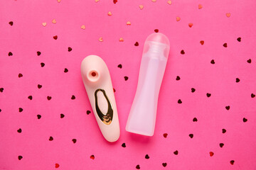 Bottle of lubricant and vibrator on pink background