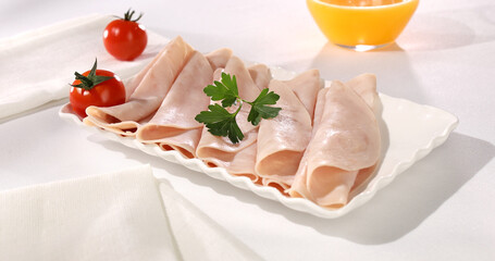 ham on a plate. meat delicacy with cherry tomato on a light background. turkey ham slices with...