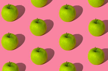 Trendy fruit pattern made of green apples on light pastel pink background. Minimal layout. Nature summer concept.