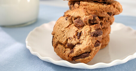 cookies with milk on a blue background. american chocolate chip cookie closeup. pastries on the table. sweets on a plate on a sunny day