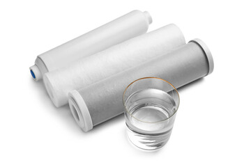 Glass of liquid and water filter cartridges on grey background