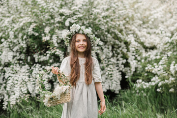 Cute stylish child girl 5-6 year old with white flowers wear floral wreath and rustic dress outdoor...