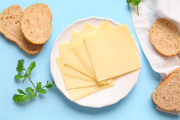 Plate of tasty processed cheese with bread on blue background