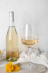 Bottle and glass of dandelion wine on white table