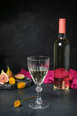 Bottle and glass of dandelion wine on dark table