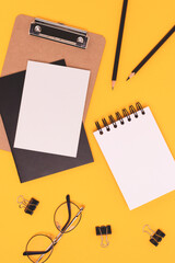 Black colored school supplies on a yellow background. Blank notepad.