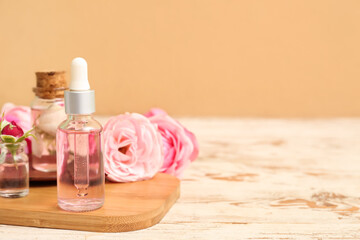 Fototapeta na wymiar Bottles of cosmetic oil with rose extract and flowers on light wooden table
