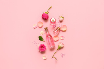 Bottles of cosmetic oil with rose extract and flowers on pink background