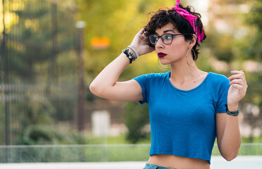 retrato de bella mujer adolescente descansando después de andar en skate en la ciudad con maquillaje y anteojos, estilo 80s 90s en la ciudad.