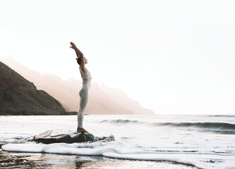 Woman is practicing yoga on the beach.