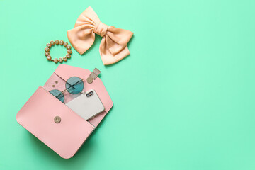 Obraz premium Stylish bag with mobile phone and different accessories on turquoise background