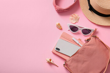Stylish bag with mobile phone and different accessories on pink background