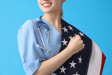 Female doctor with USA flag on blue background, closeup - obrazy, fototapety, plakaty