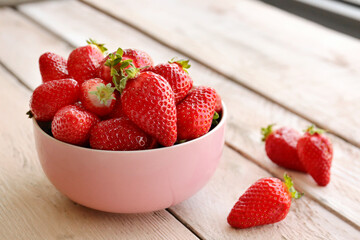 Bowl with fresh strawberries on white wooden table