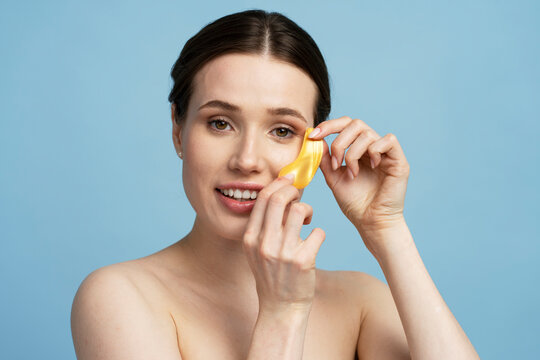 Portrait of beautiful young woman applying golden under eye patches