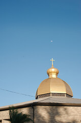 Fototapeta na wymiar dome of orthodox church Cross Pointing up to Sky to a small moon in a blue sky