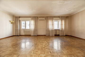 An empty house with a large living room with several curtained windows