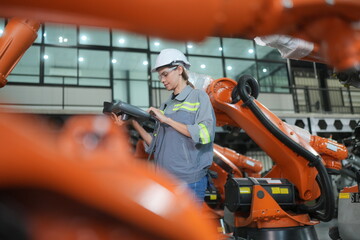 Mechanical engineers with robotic welder. Programming development technology work.. Female industrial engineer working at automated AI robotic production factory..