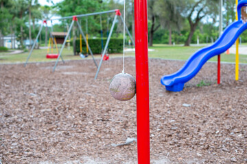 Multiple plastic and rubber swings hanging from chains in a children's park. There's a blue plastic...