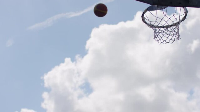 Basketball sailing through the air to the hoop before missing and hitting the ring, in slow motion