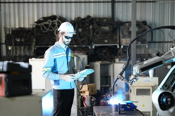 Robotics engineer working on maintenance of robotic arm in factory warehouse. Business technology.