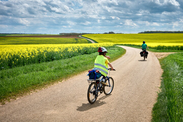 Obraz premium Aventures en famille avec les voyageurs à vélo à travers les champs de colza jaune en France