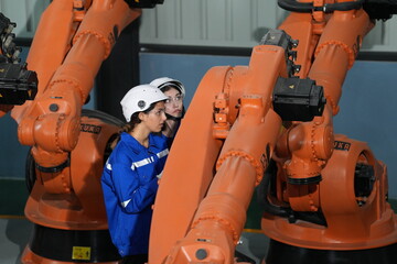 Robotics engineer working on maintenance of robotic arm in factory warehouse. Business technology.