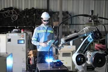 Fototapeta premium Robotics engineer working on maintenance of robotic arm in factory warehouse. Business technology.