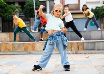 Gordijnen Cute blonde preteen b-girl dancing with group of friends on city street. Urban lifestyle. Hip-hop generation © JackF