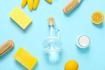 Jug of vinegar, baking soda, brushes, sponges and lemons on color background
