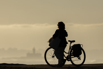 Fototapeta na wymiar Silhouette of a woman with a bicycle at sunset