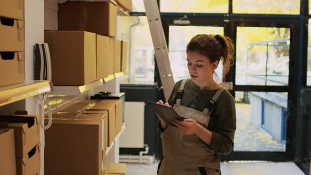 Woman answering landline phone call talking to headquarters before doing quality control. Young adult inspecting merchandise for order shipment and delivery, small business production.