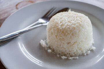 White rice with spoon and fork on white plate. The photo is suitable to use for food background, menu poster and content media.