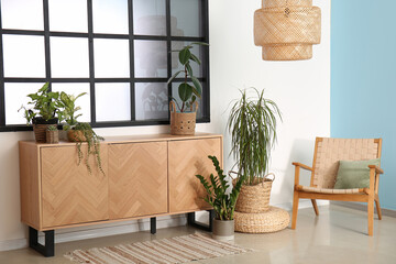 Minimalist interior of living room with wooden cabinet and cozy armchair near window