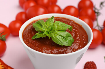 Bowl of delicious tomato sauce with basil leaves on lilac background, closeup