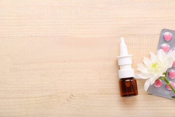 Nasal drops with flower and pills on light wooden background. Seasonal allergy concept