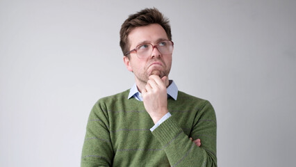 A European young man is rubbing his chin in doubt, thinking and making plans.
