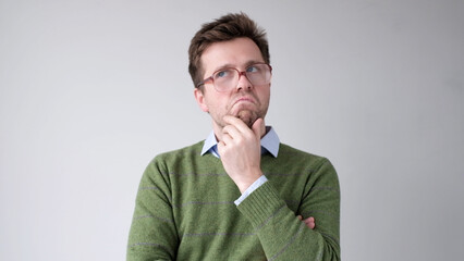 A European young man is rubbing his chin in doubt, thinking and making plans.