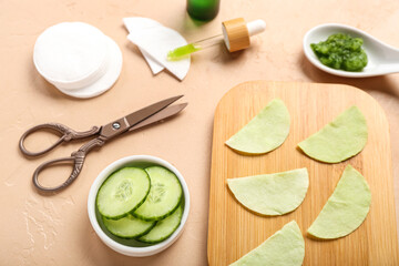 Cotton under-eye patches with cucumber slices and materials on beige background