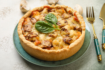 Mushroom pie with spinach leaves and cutlery on green grunge table
