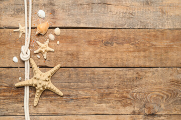 Seashells and starfishes with rope on brown wooden background