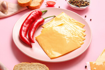 Plate of tasty processed cheese with bread and chilli on pink background