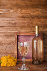 Bottle and glass of dandelion wine on wooden table