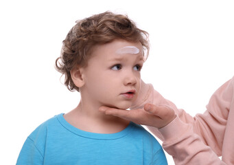 Mother applying ointment onto her son`s forehead on white background